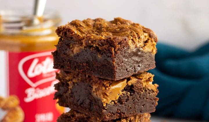 A stack of three brownies with peanut butter on top.